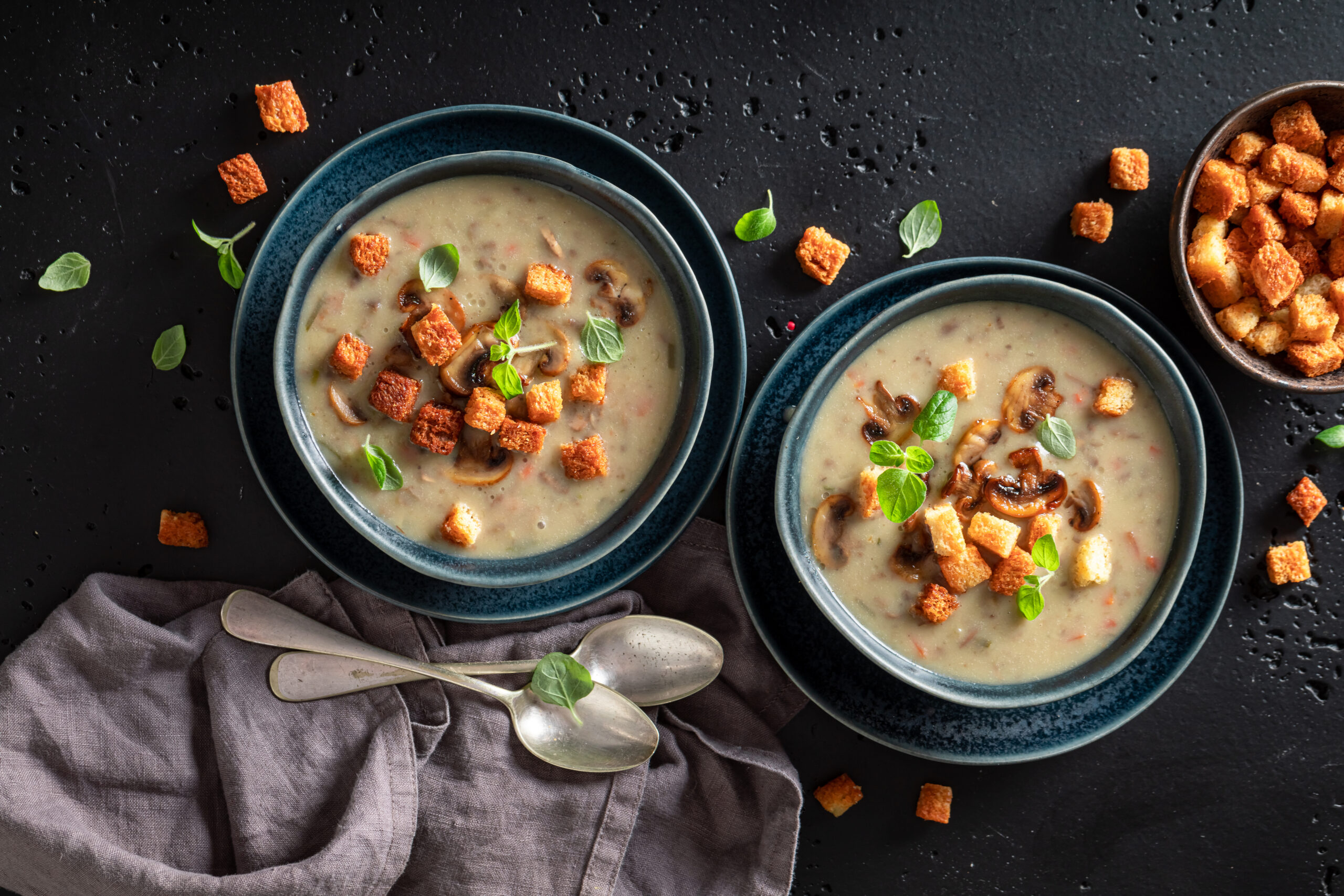 Two bowls of creamy mushroom soup with croutons