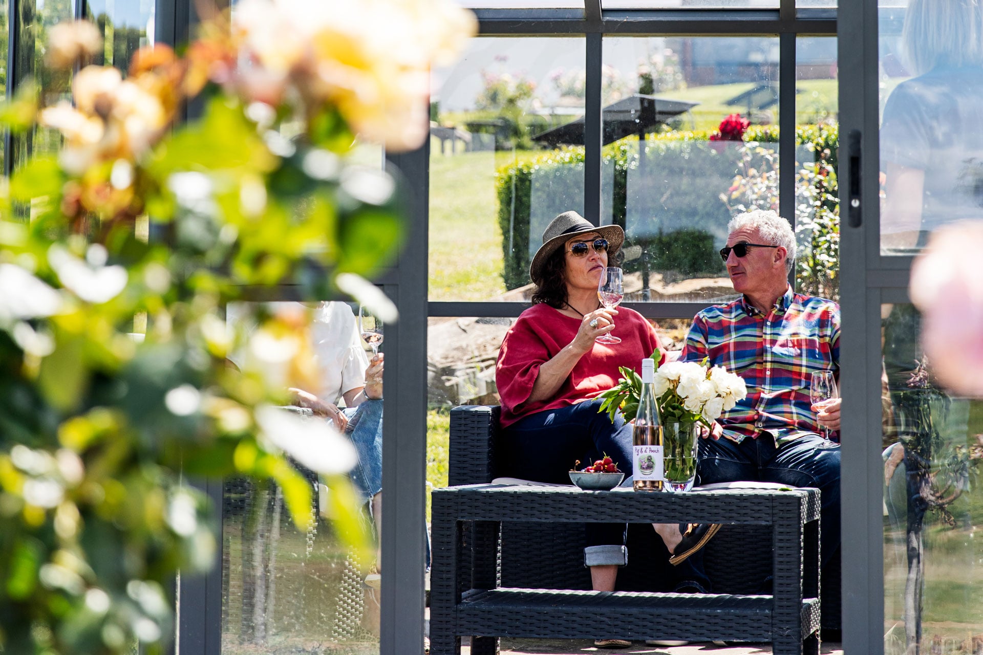 A couple sitting in the sun enjoying a glass of wine